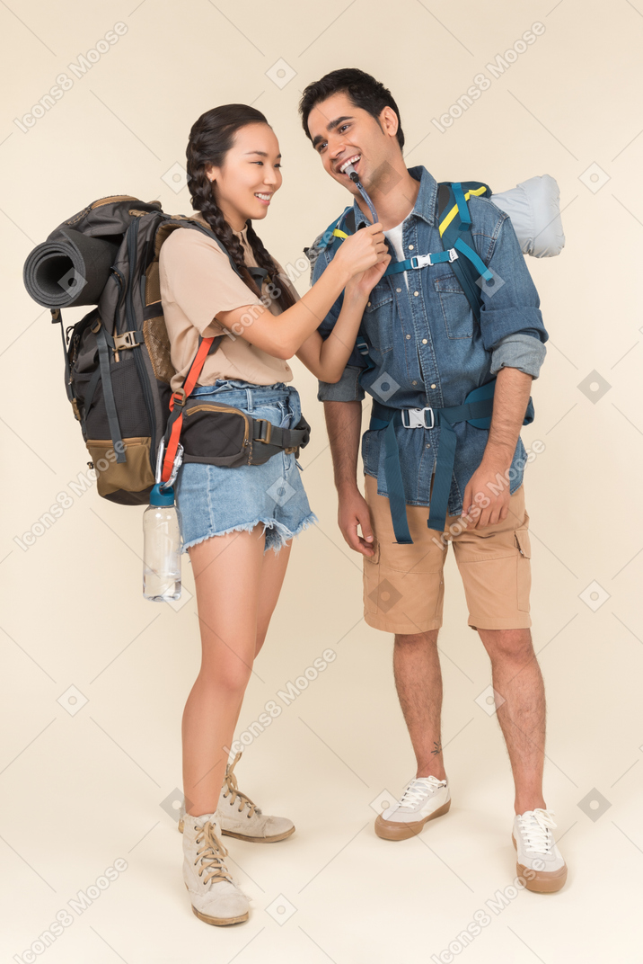Casal interracial de caminhantes com mochilas enormes rindo