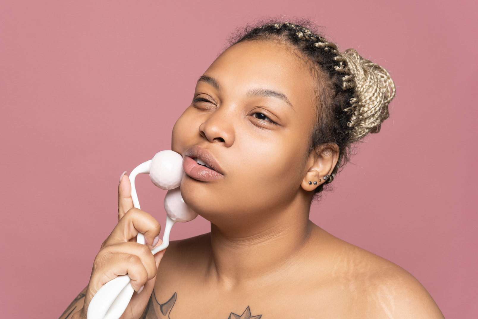 Black woman doing a face massage with a roller aplicator