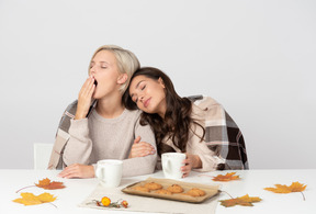 Giovani donne che bevono caffè mattutino e sbadigliano