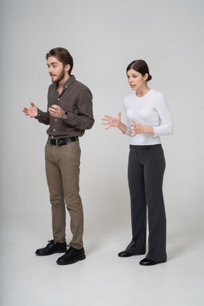 Vista di tre quarti di una giovane coppia interrogativa in abiti da ufficio