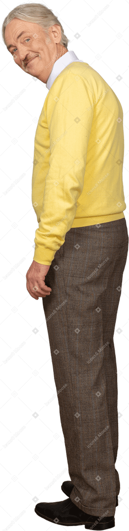 Vista posteriore di tre quarti di un uomo anziano che indossa un pullover giallo e sorride mentre guarda la fotocamera