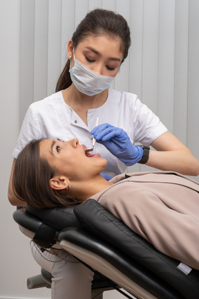 Una foto de un dentista examinando con cautela a su paciente asustada