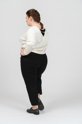 Mulher gorda com suéter branco posando com as mãos na cintura