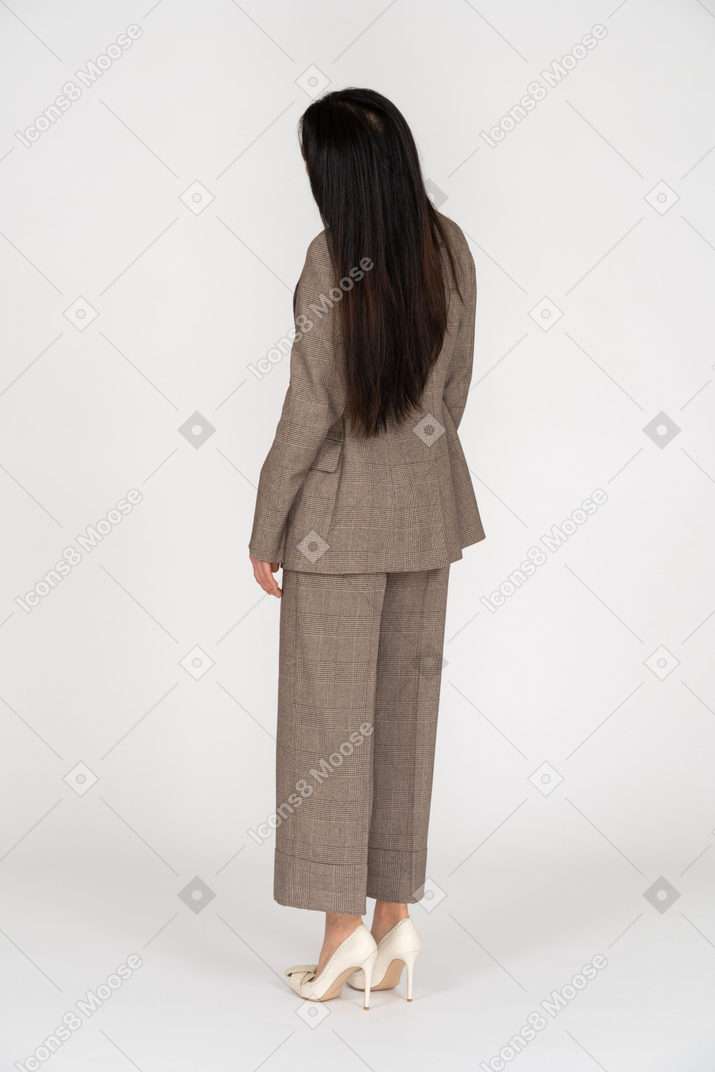 Vista de três quartos das costas de uma jovem de terno marrom inclinando a cabeça