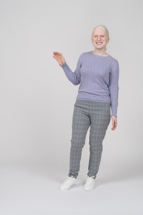 Mujer joven sonriendo y levantando la mano