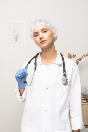 Vista frontal de una joven doctora sosteniendo estetoscopio