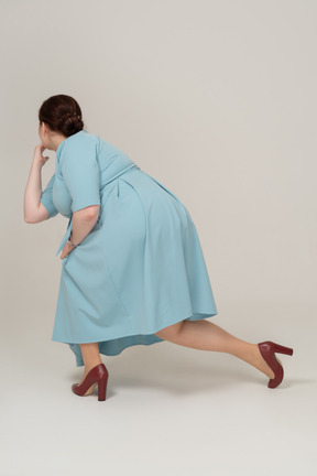 Vista laterale di una donna in abito blu accovacciata
