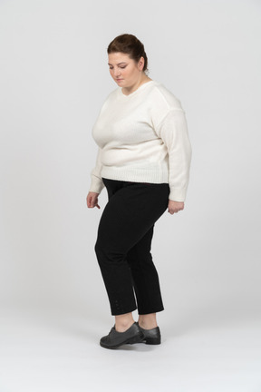 Mulher gorducha em suéter branco em pé com as mãos atrás da cabeça