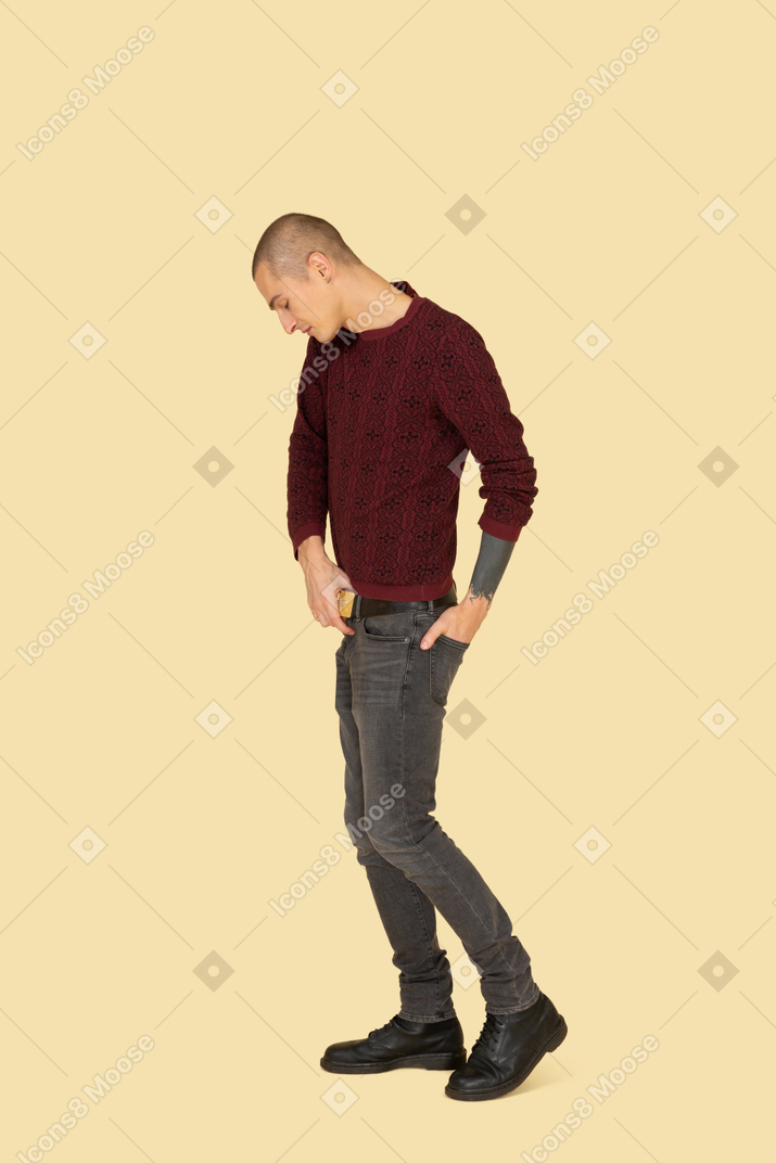 Side view of a young man in red pullover touching belt