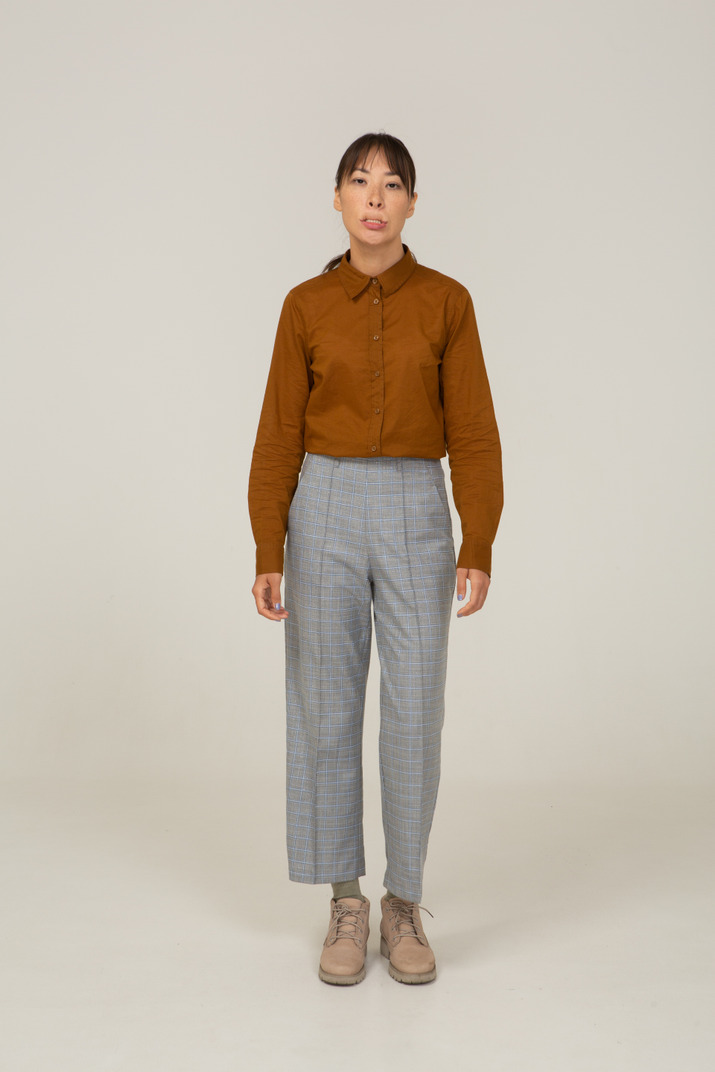 Front view of a grimacing young asian female in breeches and blouse biting lips