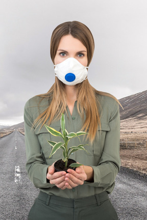 A woman wearing a face mask holding a plant