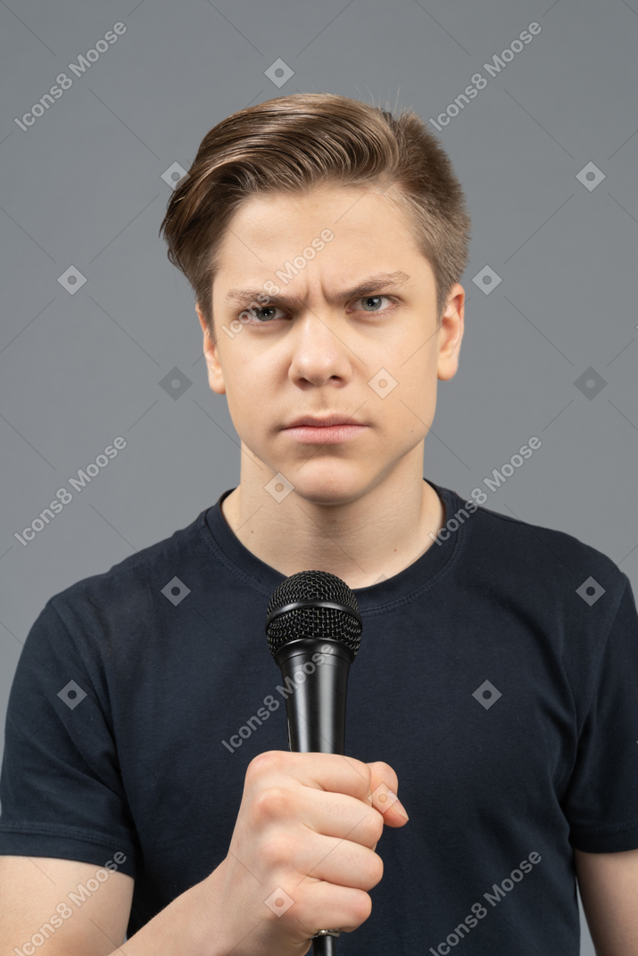 Ernsthafter junger mann mit einem mikrofon