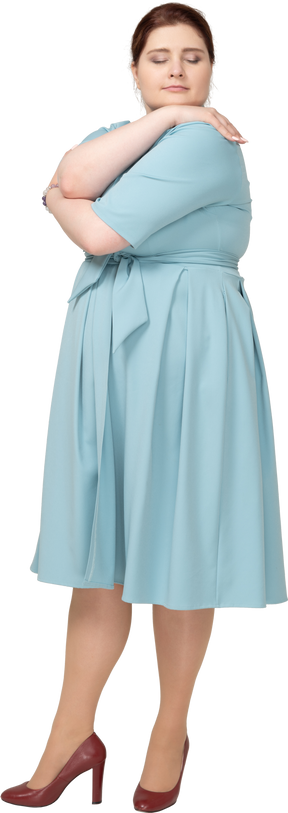 Вид спереди женщины в синем платье, обнимающей себя