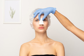 Nurse applying gauze to young woman's nose