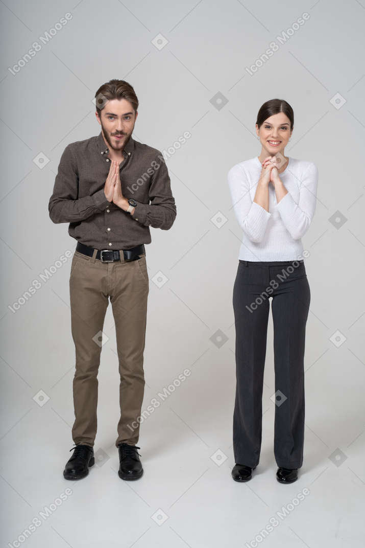 Vista frontal de um jovem casal satisfeito com roupas de escritório, de mãos dadas