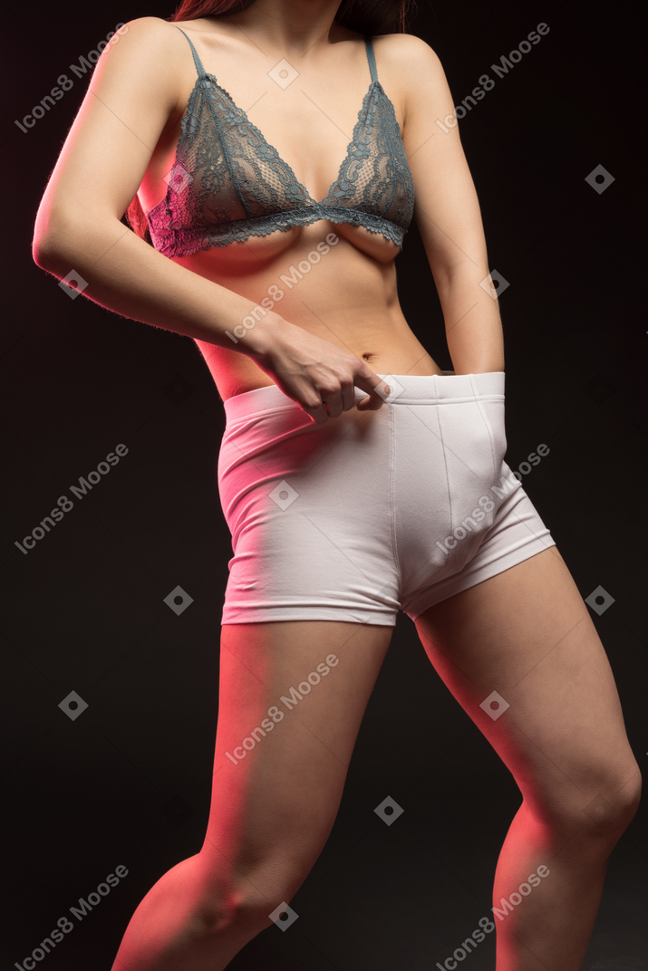 Close-up of sensual naked young woman putting something in boxers