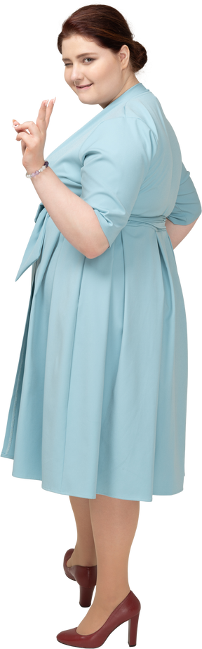 Vista lateral de uma mulher de vestido azul mostrando o sinal v