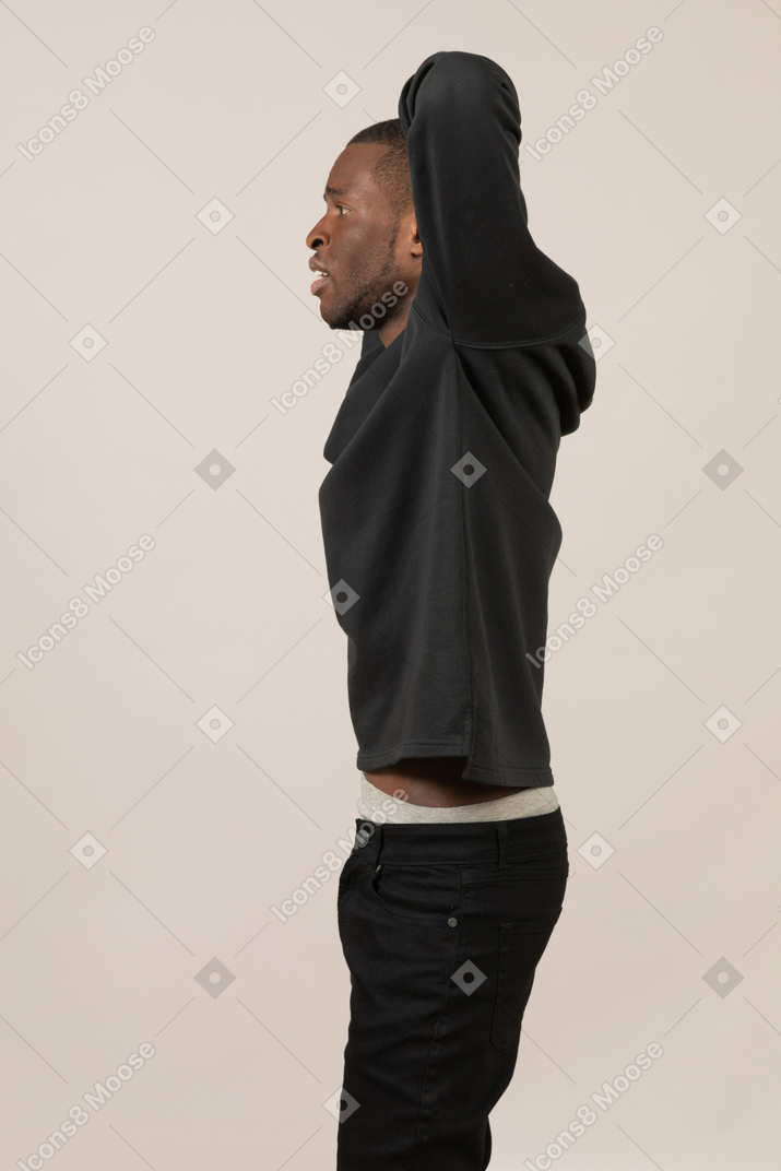 Side view of young man stretching arms