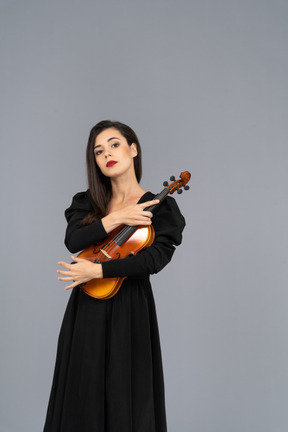 Vue de face d'une jeune femme en robe noire tenant le violon