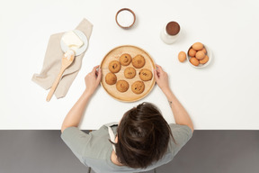 Um padeiro feminino segurando um prato de biscoitos