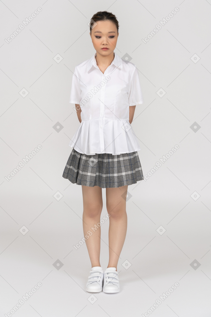 Quite asian girl standing with hands behind her back