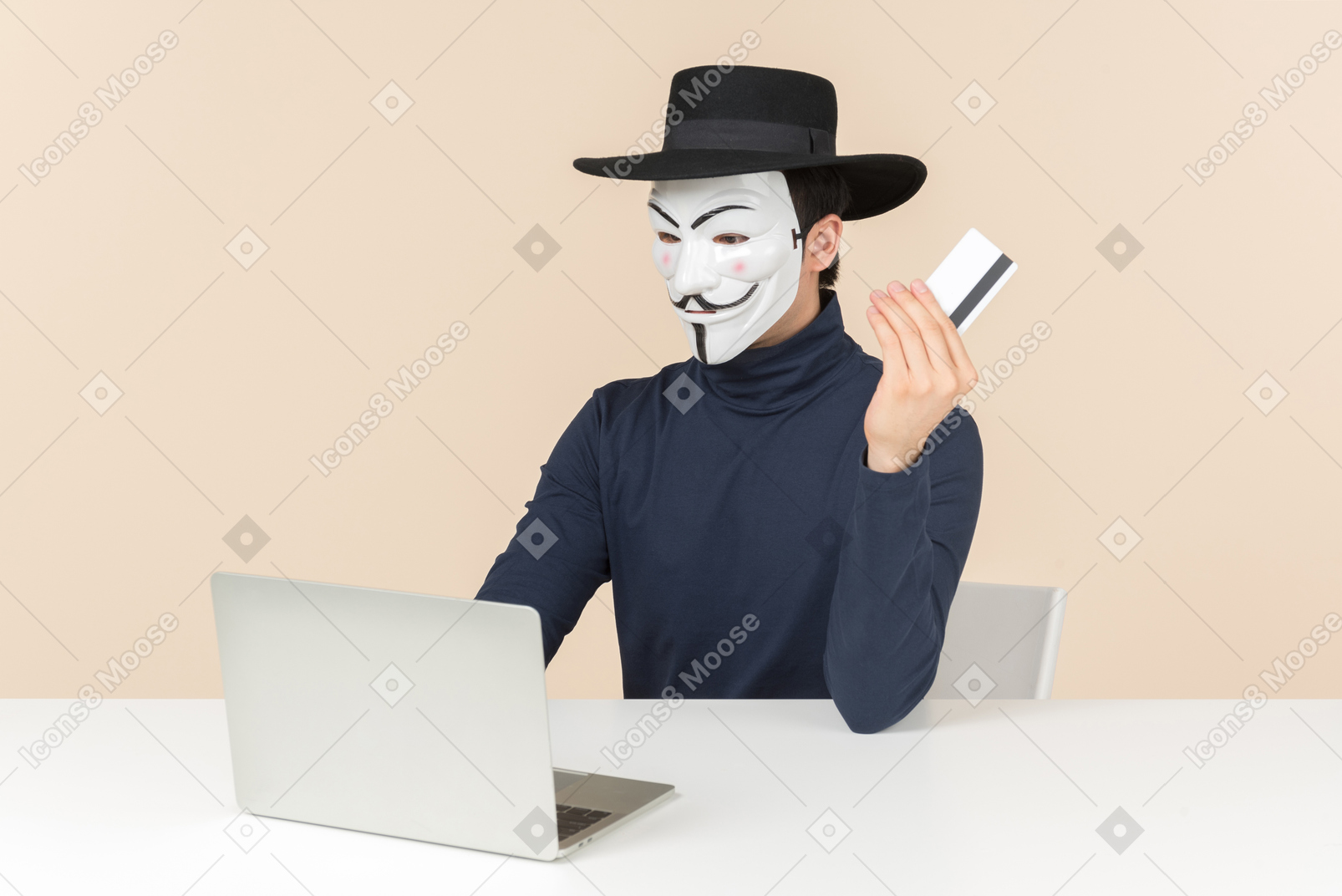 Хакер в маске вендетты сидит за ноутбуком и держит карточку бак