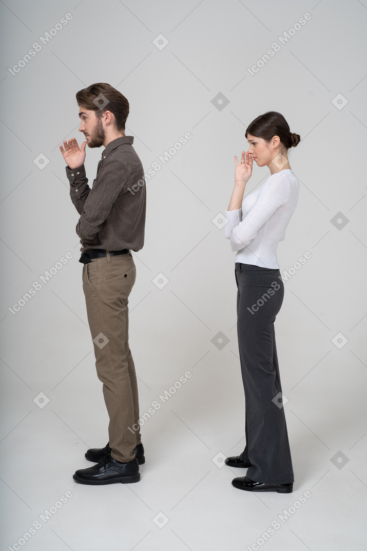 一对年轻夫妇穿着办公室服装闻到难闻气味的侧视图