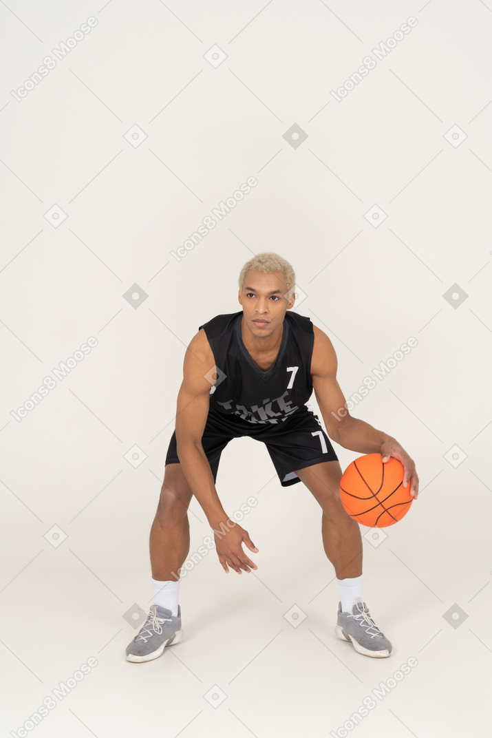 Front view of a young male basketball player doing dribbling