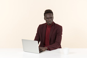 Elegante hombre negro sentado a la mesa en la oficina