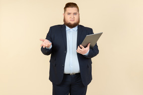 Young overweight office worker seems like not getting something and holding digital tablet