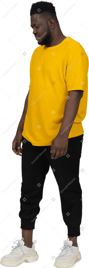 Visão de três quartos de um jovem de pele escura em uma camiseta amarela parado