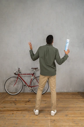 Back view of a man gesturing holding a map in hand and looking up