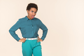 Black woman with a short haircut, wearing all blue, standing against a plain pastel background, looking emotional