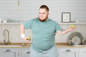 A fat man holding two apples in his hands