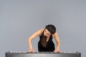 Vista frontal de uma jovem de vestido preto tocando piano