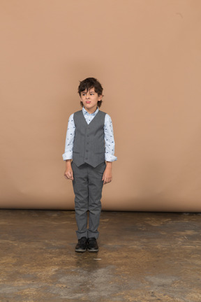 一个穿着灰色西装的可爱男孩站着不动的前视图