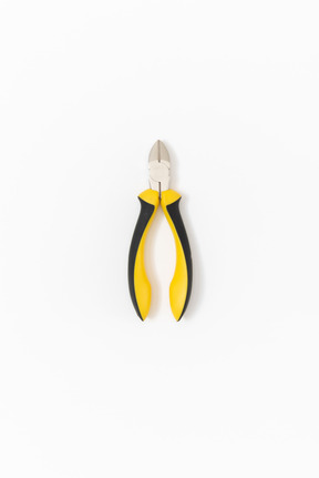 Closed nippers with a bright yellow and black handle lying on a plain white background