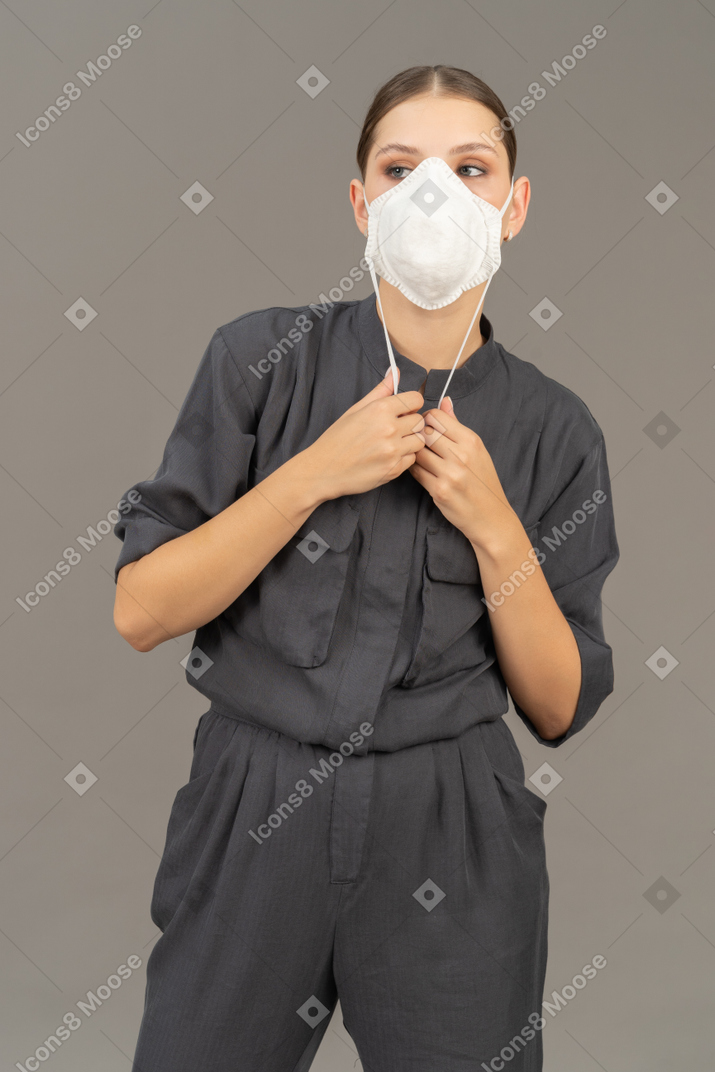 Mujer con overoles grises usando un respirador