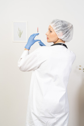 注射器を保持している若い女性医師の背面図