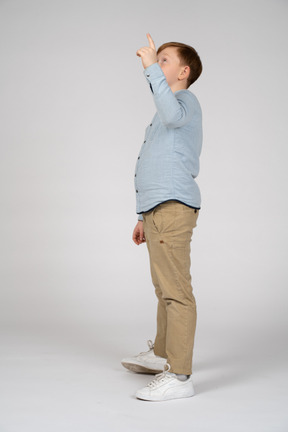 Boy in blue shirt and khaki pants pointing and looking up