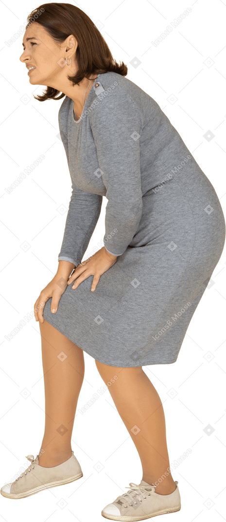 Side view of a woman in grey dress touching knee