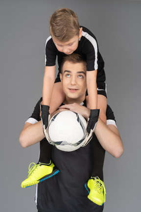 Close-up of a football player holding little boy on his neck