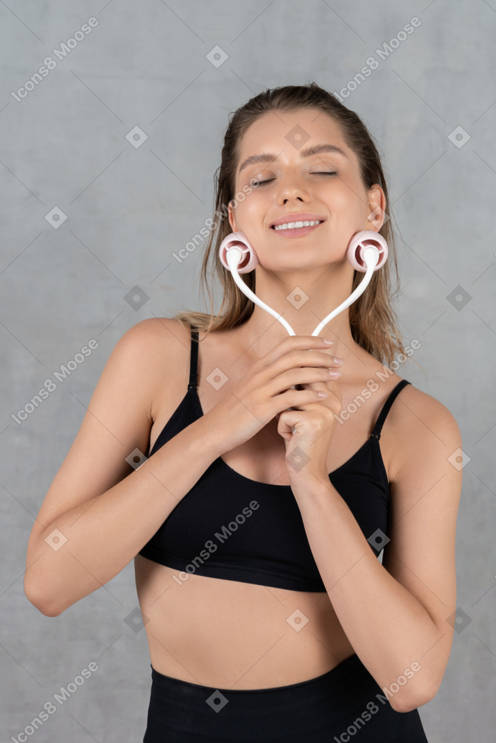 Portrait of a young woman feeling relaxed while using face massager
