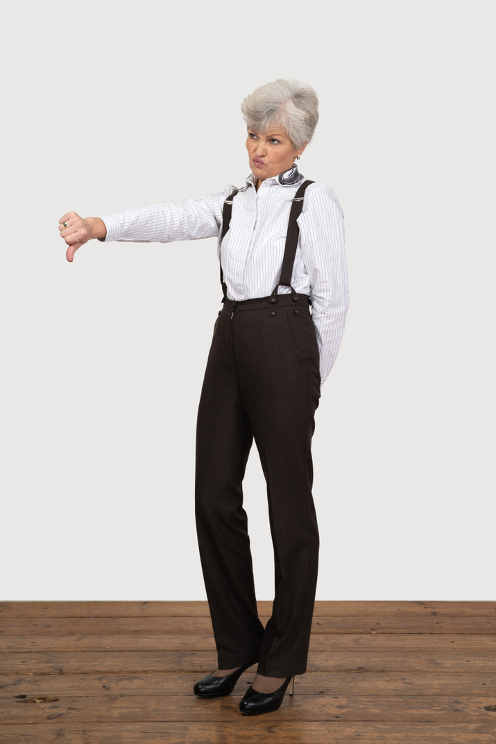 Three-quarter view of an old lady in office clothing putting thumb down