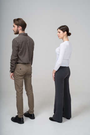 Three-quarter back view of a young couple in office clothing standing still