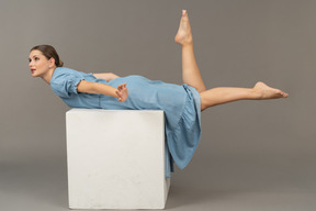 Side view of young woman lying on cube