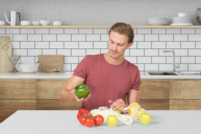 A man holding a bell pepper while standing in a kitchen