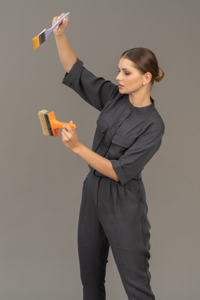 페인트 브러시를 선택하는 회색 작업복을 입은 여성