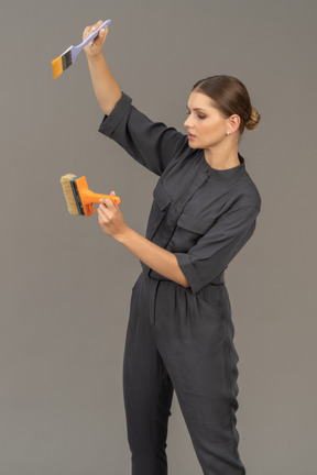 Woman in gray coveralls choosing a paint brush