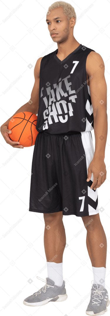 Vista de tres cuartos de un joven jugador de baloncesto masculino sosteniendo una pelota